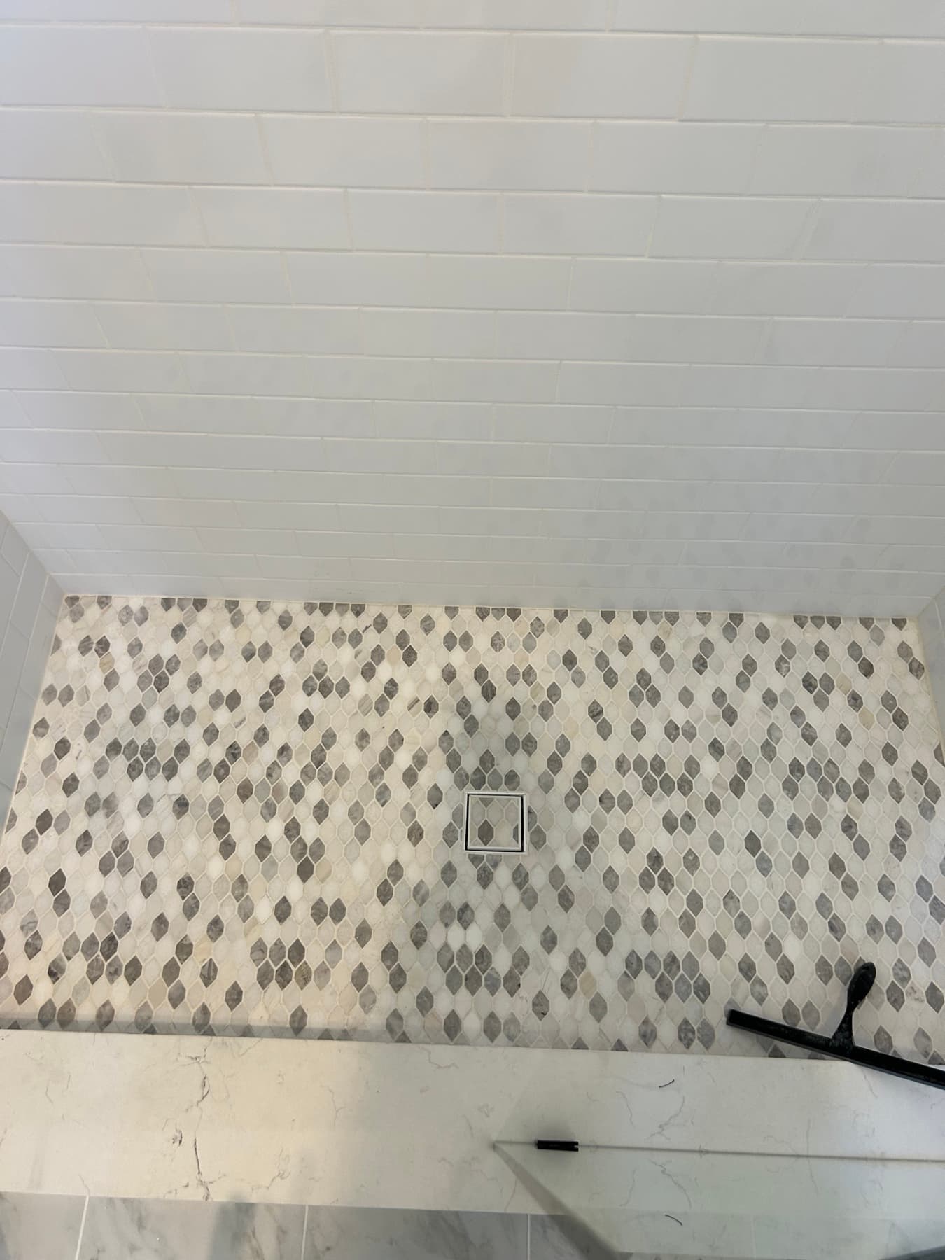 Marble shower with a pebble mosaic accent